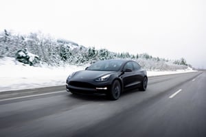 Tesla Model 3 serba listrik yang melaju di jalan raya dua jalur selama kondisi musim dingin.